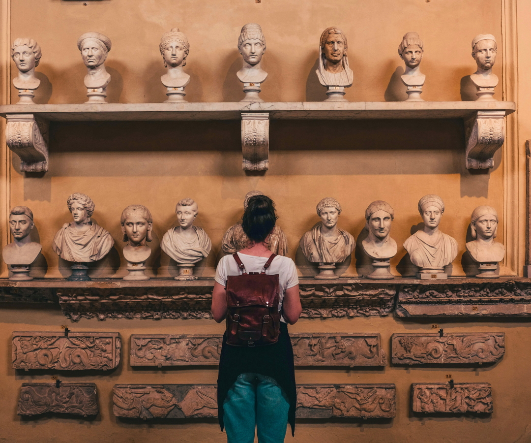 A Vatican visitor looks at small busts on the wall.